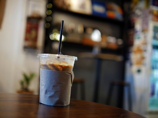 Iced coffee in a plastic mug placed on a table in a coffee shop Blurred image