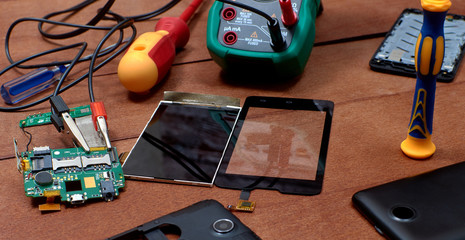 Mobile phone disassembled. Multimeter. Motherboard of the mobile phone. Mobile phone repair shops. The screen and touchpad of the mobile phone. Electronics repair tool. double-sided tape.