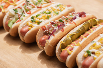 selective focus of fresh various delicious hot dogs with vegetables and sauces on wooden table