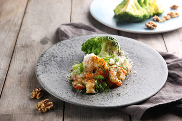Seafood cuisine. Shrimp with broccoli, cheese, walnuts and herbs on a grey background. Background image, copy space