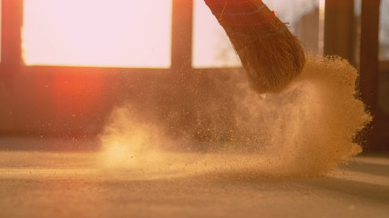 LOW ANGLE: Dust gets swept up into air as person cleans a construction site - obrazy, fototapety, plakaty