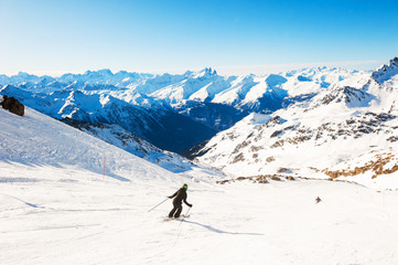 Fototapeta na wymiar Skier rides down the slope in Alps mountains. Winter sport. Val Thorens, 3 Valleys, France. Beautiful mountains, winter landscape