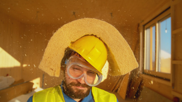 CLOSE UP: Male surveyor with a beard gets struck in the head by a piece of foam.