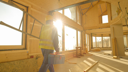 CLOSE UP: Golden sunbeams shine on worker coming to work in prefabricated house