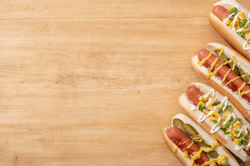 top view of delicious hot dogs with corn, green onion and pickles on wooden table
