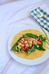 Chickpea flour tortilla wraps filled with spinach, tomato, avocado, onion and sesame seeds