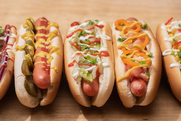 fresh delicious hot dogs with sauces on wooden table
