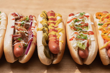 fresh various tasty hot dogs with vegetables and sauces on wooden table