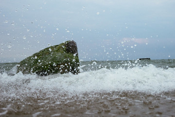 Bubbling water in a sea in summer time. Flowing water close up. Nobody. Stone and  fast cold grey water. Travel and adventure.  Water droplets. European nature in hot season without people. Beach.