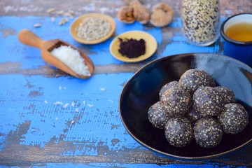 Maqui berry energy balls with quinoa, fig, sunflower seed and coconut flakes. Blue background
