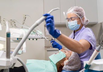 The dentist using specialized tools treats caries in the patient’s oral cavity using new technologies in dentistry.