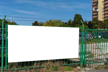 Blank white banner for advertisement on the fence. Residential area on a sunny summer day. © diesirae