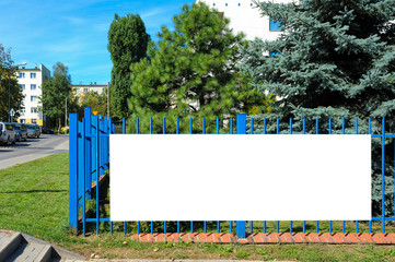 Blank white banner for advertisement on the fence. Residential area on a sunny summer day.