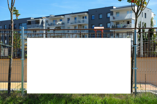 Blank white banner for advertisement on the fence. Residential area on a sunny summer day.
