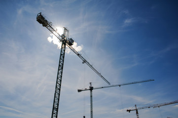 Obraz premium Steel construction cranes on the blue sky background