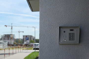 Modern intercom with video camera. Construction site with cranes in the background