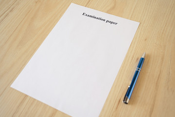 Empty examination paper for university with pen on the school desk. Copyspace. Mockup. Flat lay