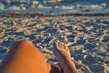 Urlaubsfeeling, Blick über Beine, Zehen voll Sand am Strand von Sanibel Island