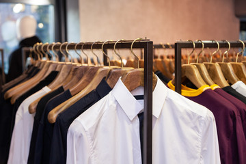 Closeup colorful male, female clothes in boutique hanging on hangers, clothing rack on metal stand....