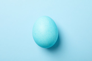 Blue Easter egg on blue background, close up