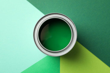 Can of green paint on multicolored background, top view