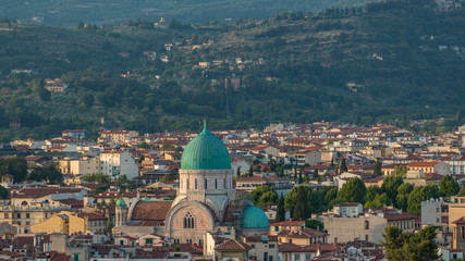 Fototapeta na wymiar Synagogue of Florence timelapse with green copper dome rising above surrounding suburban housing with green hillside behind