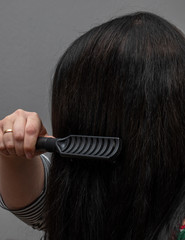 Frau mit langen schwarzen Haaren kämmt ihre Haare 