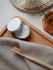 bamboo toothbrush with natural paste and beige cotton towel, little plant on the white background. Concept eco friendly, zero waste.