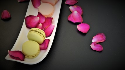 multicolored french macarons with rose petals on a white dish