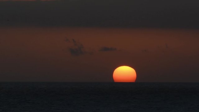 El sol , convertido en una esfera roja, se esconde tras el horizonte del mar