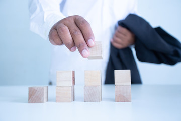 Businessman Wooden cubes on a desk in the office, Concept: Business to succeed that challenges teamwork,  design development strategy investment, symbol Financial advisor shows  to asset growth