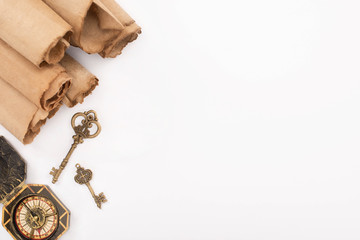Fototapeta premium top view of vintage keys, compass and rolled aged paper isolated on white