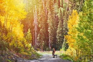 A young woman hiking with her dog in the mountains of Colorado