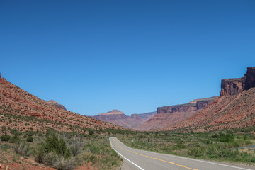 Landscape of road in a valley flanked by colorful stone hillsides in western Colorado