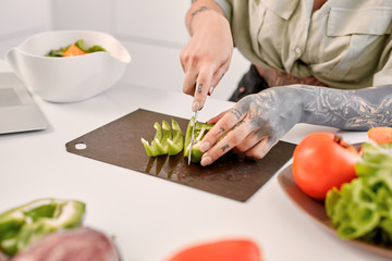 Young adult girl cutting pepper, cooking on kitchen