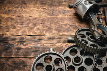 Old car spare parts on brown wooden workbench background with copy space.