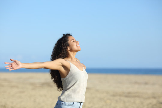 Relaxed woman breathing with open arms on the beach