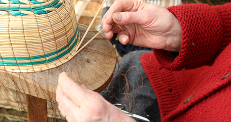 skilled hands of the elderly craftswoman while creating a basket