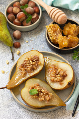 Healthy diet dessert. Baked pears with hazelnuts, honey and granola on a slate, stone or concrete background.