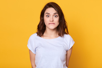 Beautiful woman dresses casual clothes, looking nervously directly at camera, feeling distrust or...