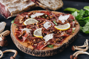 Carpaccio of the dried salty beef with mushroom on the black table. Top view