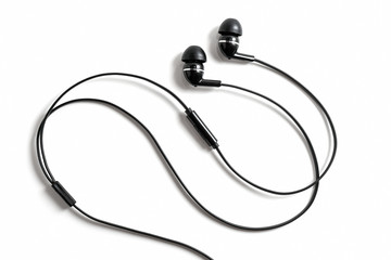 Vacuum black wired earplugs for listening to music and sound on portable devices on a white background. Headphones headset. In-ear headphones for music lovers.