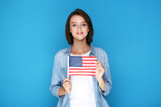 Beautiful young woman holding american flag on blue background