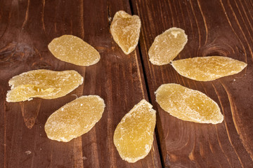 Group of eight slices of dried yellow pineapple on brown wood