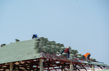 Construction worker install new roof tile for new house.