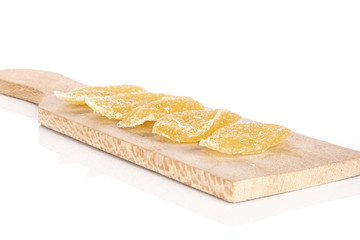 Group of five slices of dried yellow pineapple on wooden cutting board isolated on white background