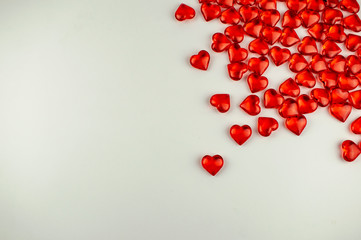 A scattering of scarlet crystal hearts on a white background.