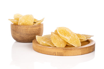 Lot of slices of dried yellow pineapple in bamboo bowl on round bamboo coaster isolated on white background
