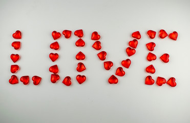 Love inscription made of crystal hearts on a white background.