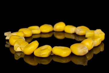 Lot of pieces of canned yellow corn circle isolated on black glass